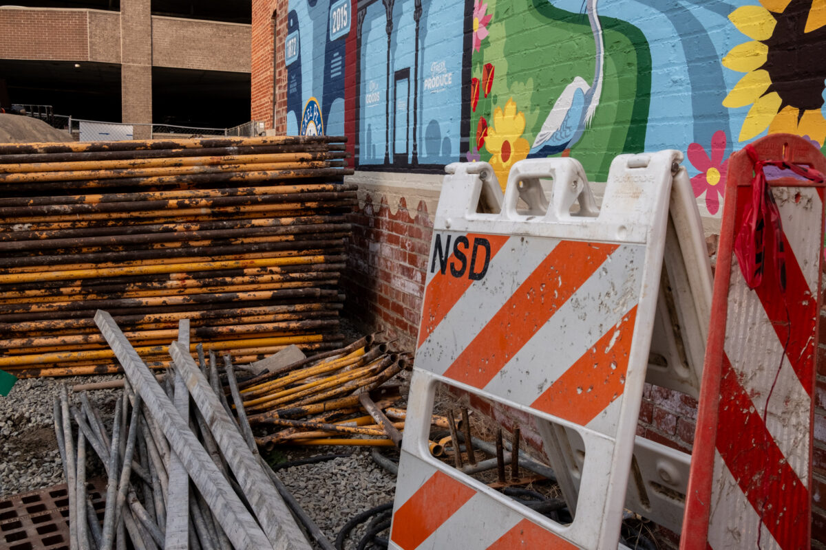 "Construction & Mural" ©Zach Dobson Top 10 Photos 2024 
 Construction materials stacked next to a mural painted on a brick wall. Fishers, Indiana.