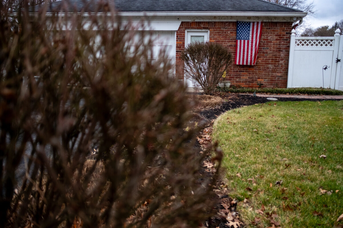 "Flag in Winter" ©Zach Dobson Top 10 Photos 2024  Suburban ranch home with brick siding and American flag hanging from the side. Carmel, Indiana.