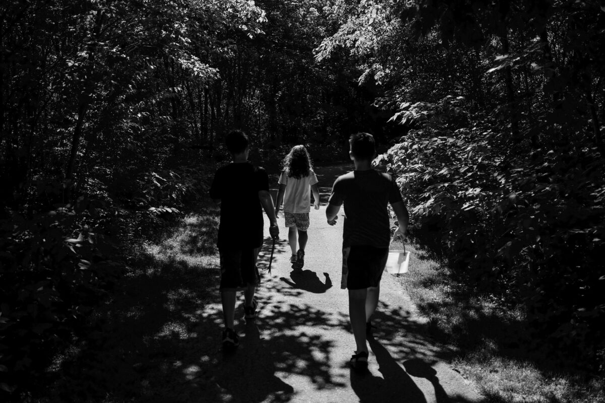 kids walking down a path in the woods black and white