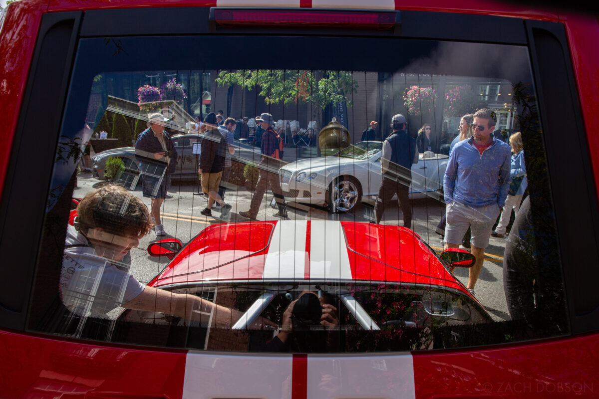 The rear hood of a Ford GT that covers its engine is open and the window frames the surrounding scene