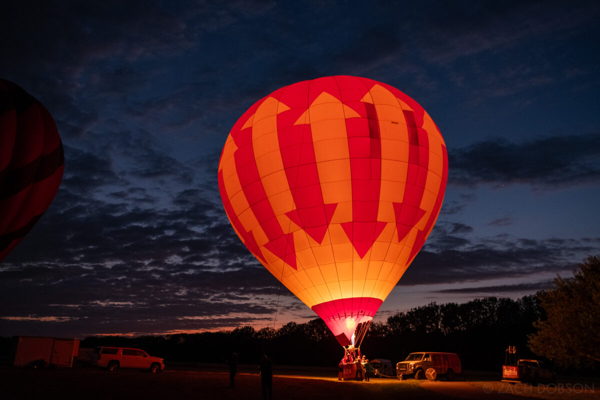 Red and yellow hot air balloon at dusk. Balloon Glow - Jupiter Flights Balloon Festival at Conner Prairie Image: Zach Dobson Photography