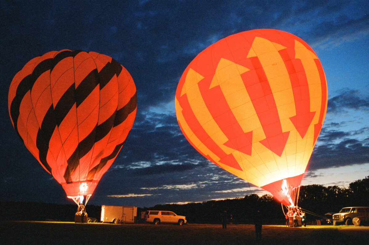 Two hot air balloons at dusk. Photographing a Balloon Glow on film - Jupiter Flights Balloon Festival at Conner Prairie Image: Zach Dobson Photography