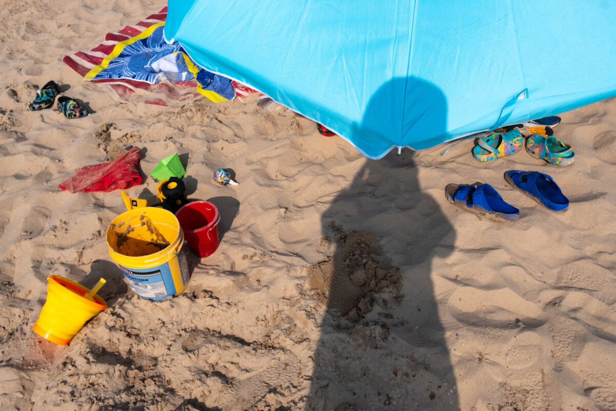 Umbrella, towels, and sand toys with photographer's shadow at Silver Beach.