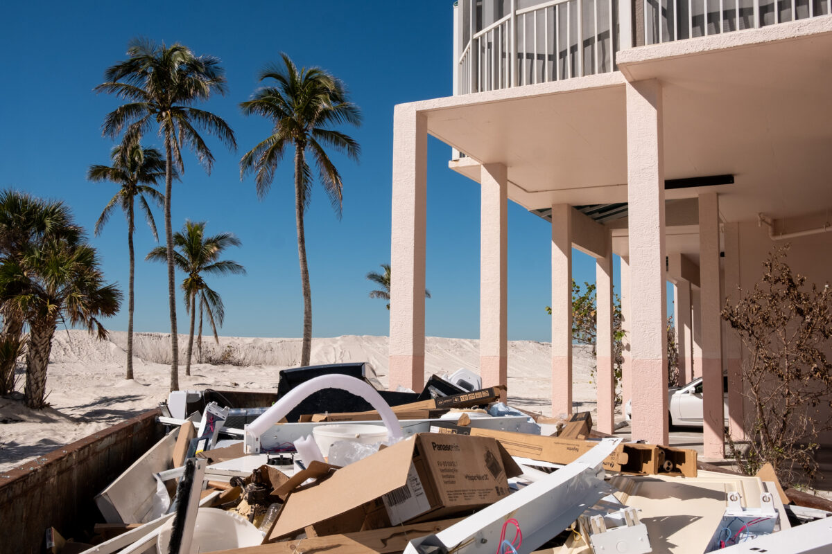 Dumpster full of construction trash outside beach condo building with palm trees. Bonita Springs, Florida.