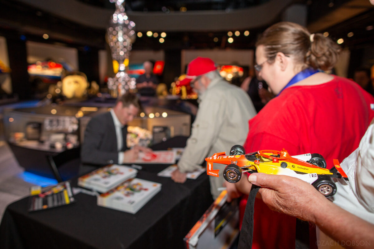 A fan waits to have a model car signed by Josef Newgarden at the Indianapolis Motor Speedway Museum