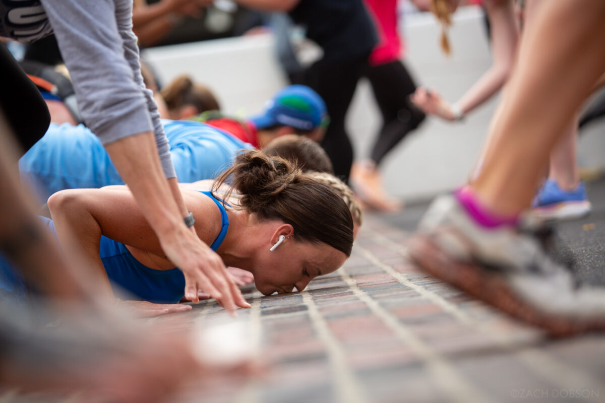 Runners stop to kiss the bricks at the Indianapolis Motor Speedway track during the 2025 Indiana University Health 500 Festival Mini Marathon in Indianapolis